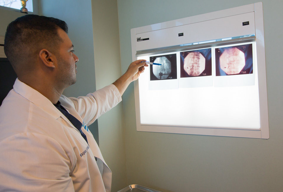 Dr. Waqaas Quraishi examining a patient's x-rays at the Orthopedic Spine Care of Long Island office.